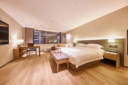 a hotel room with a large bed and a desk at Puji Hotel in Guangzhou