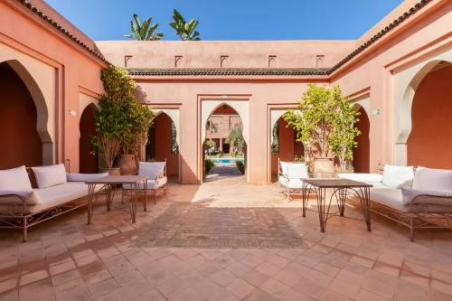 an outdoor patio with white furniture and tables at Villa Layyine avec personnel, piscine, spa et sports in Marrakech