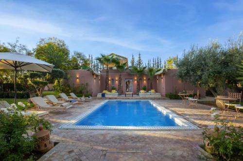 a swimming pool in a backyard with chairs and an umbrella at Villa Layyine avec personnel, piscine, spa et sports in Marrakech