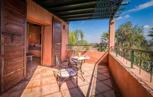 a patio with a table and chairs on a balcony at Villa Layyine avec personnel, piscine, spa et sports in Marrakech