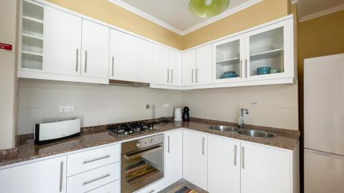 a white kitchen with white cabinets and a sink at Serra & Mar in Vila Franca do Campo