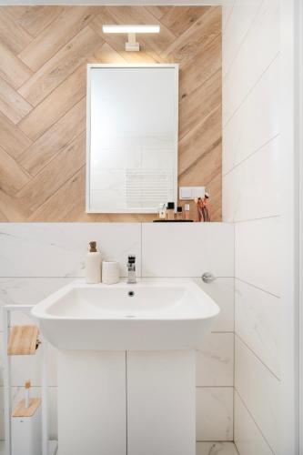 a bathroom with a white sink and a mirror at Apartamenty Fuzja - Komfortowe Mieszkania Blisko Centrum Łodzi Garaż in Łódź