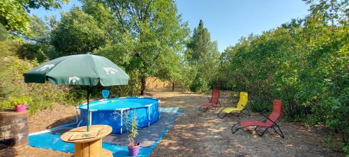 - un groupe de chaises et un parasol à côté d'un bain à remous dans l'établissement Le Jas du Tilleul, à Villecroze