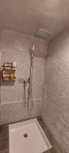 La salle de bains carrelée de blanc est pourvue d'une douche et d'une baignoire. dans l'établissement Le Jas du Tilleul, à Villecroze