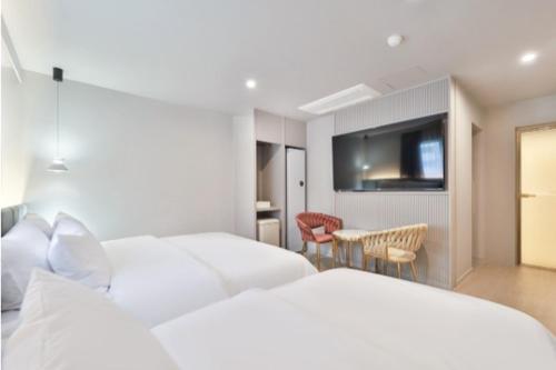 a hotel room with two beds and a table and chairs at Deokcheon Den Basta Hotel in Busan