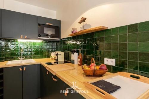 een keuken met groene tegels op de muren en een aanrecht bij La Terrasse de Pom Cozy Comfort City Center 2 Guests in Honfleur
