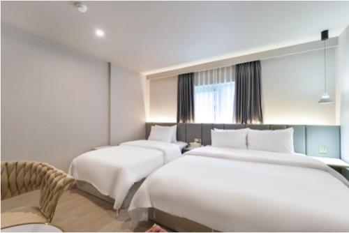 a hotel room with three beds and a chair at Deokcheon Den Basta Hotel in Busan