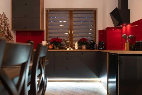 a kitchen with red cabinets and a window with blinds at Domki Bukowianka in Murzasichle