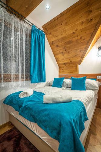 a bedroom with a large bed with blue sheets at Domki Bukowianka in Murzasichle