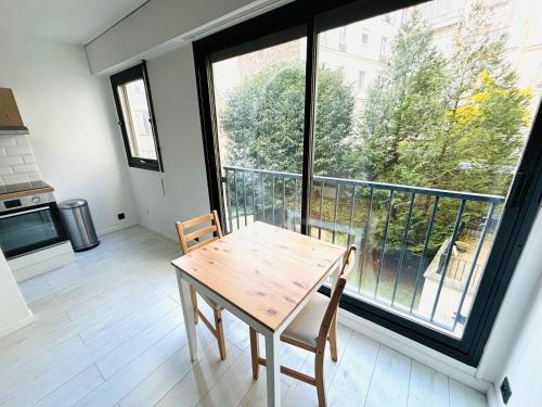 Un comedor con una mesa y un gran ventanal. en Studio Tour Eiffel La Muette, en París