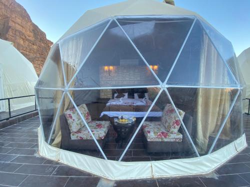 a tent with a table and chairs inside of it at Wadi Rum Santa Camp in Wadi Rum