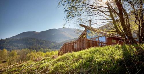 a house on top of a hill with mountains in the background at Strathyre, Ben Ledi Cabins - Forest Holidays in Callander