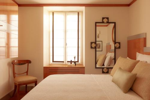 une chambre avec un lit, un miroir et une chaise dans l'établissement Au petit Rennemoulin, à Saint-Jacut-de-la-Mer