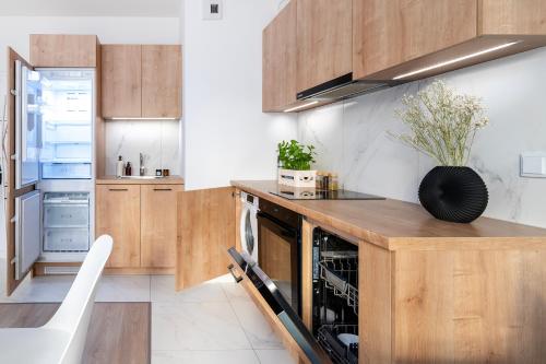 a kitchen with wooden cabinets and a counter top at Apartamenty Fuzja - Komfortowe Mieszkania Blisko Centrum Łodzi Garaż in Łódź