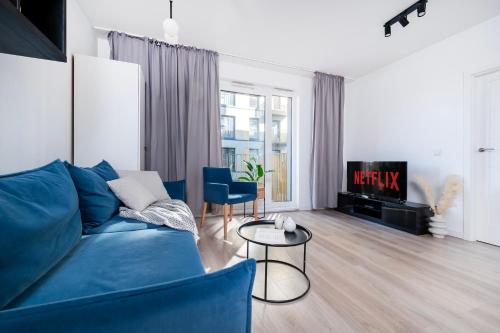 a living room with a blue couch and a tv at Apartamenty Fuzja - Komfortowe Mieszkania Blisko Centrum Łodzi Garaż in Łódź