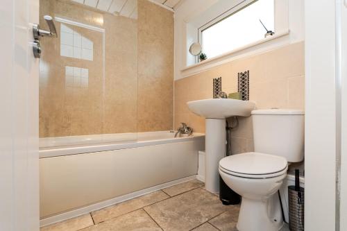 a bathroom with a toilet and a tub and a sink at 3 Bed House-Free Parking-6Beds in Cumbernauld