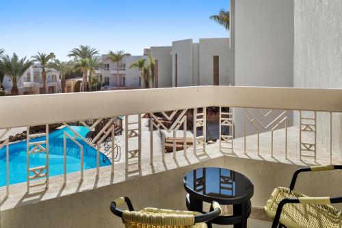a balcony with chairs and a swimming pool at DoubleTree by Hilton Sharks Bay Resort in Sharm El Sheikh