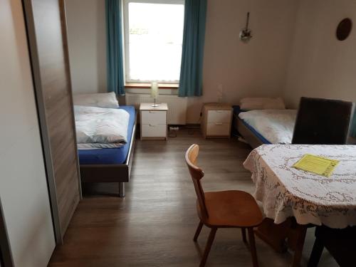 a room with two beds and a table and a chair at Gästehaus Erika in Marschall