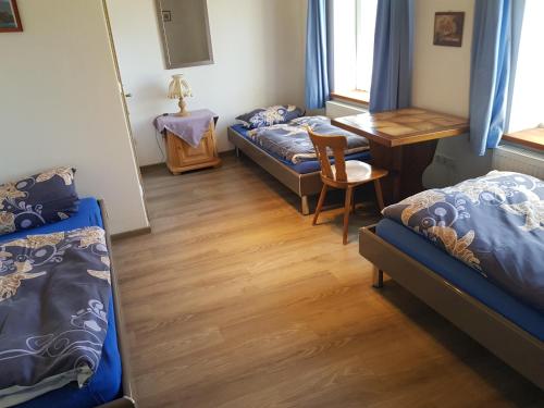 a room with two beds and a table and a desk at Gästehaus Erika in Marschall