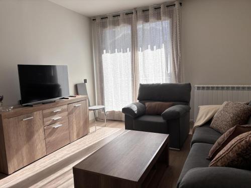 Una sala de estar con un sofá y un televisor de pantalla plana. en BPirineos-Barbarisa, en Benasque