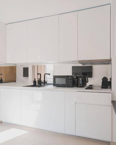 une cuisine blanche avec des armoires blanches et un micro-ondes dans l'établissement Nice Colors à coté de la plage, de la promenade des anglais et de la gare, à Nice