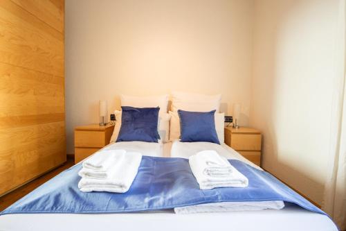 a bed with blue and white sheets and blue pillows at Special ROGER F RABBIT 2 Apartment, Roche Towers, 10-STAR in Basel