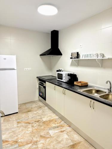 a white kitchen with a sink and a refrigerator at La Casa Del Recreo in Cómpeta