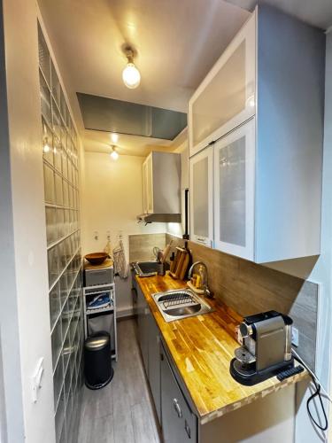 une cuisine avec des armoires blanches et un comptoir en bois dans l'établissement Beautiful stay in Paris, à Paris
