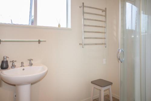 a white bathroom with a sink and a shower at The Willow - Hanmer Springs Holiday Home in Hanmer Springs