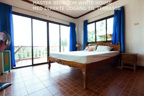 a bedroom with a bed with blue curtains and windows at RELAX White house, Puerto Galera in Puerto Galera