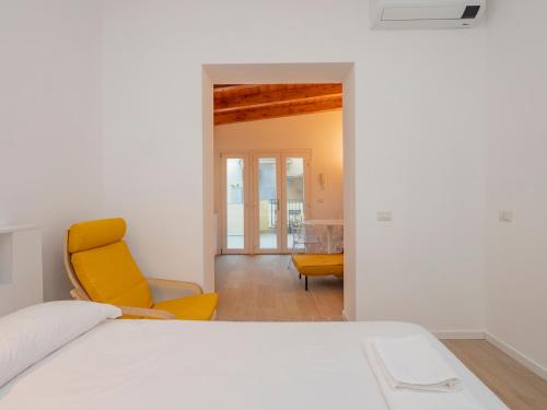 a bedroom with a bed and a yellow chair at Luxury apartment - Flumendosa 5 in Milan
