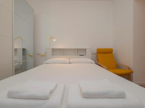 a bedroom with a white bed and a yellow chair at Luxury apartment - Flumendosa 5 in Milan