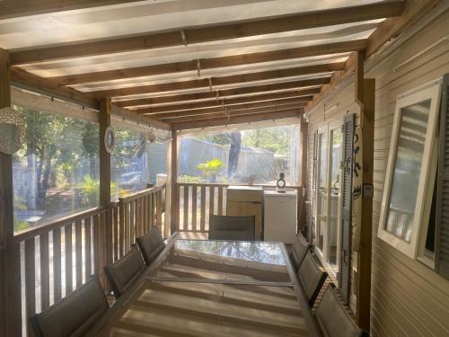 une terrasse couverte couverte avec une table et des chaises dans l'établissement MH 007 ELITE 3 chambres dont suite parentale et 2 salles de bain sur magnifique parcelle dans camping 4 étoiles, à Saint-Julien-en-Born
