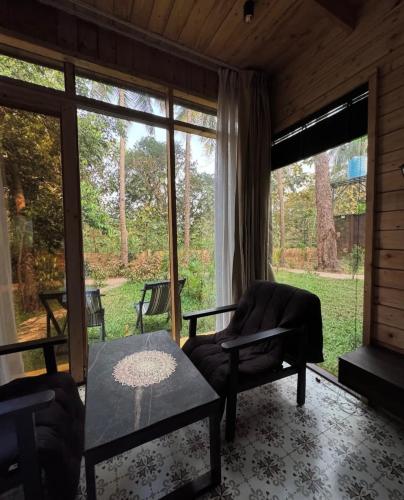 a living room with a couch and a table and windows at Maya Nature Retreat by Ella's Escape in Mandrem