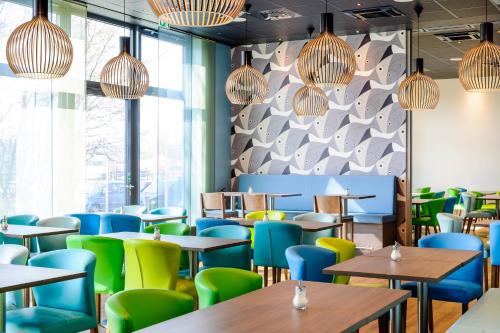 um restaurante com mesas e cadeiras e uma parede de janelas em Ibis Styles Konstanz em Constança