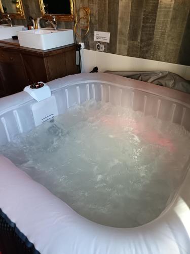 une baignoire remplie d'eau à côté d'un lavabo dans l'établissement La Pensine du célèbre sorcier, à Bourogne