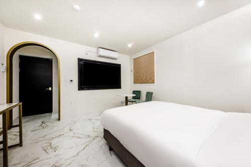 a white bedroom with a bed and a flat screen tv at Hotel eila in Pohang