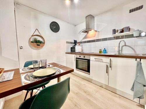 a kitchen with a wooden table and green chairs at Studio du Clocher - Centre Historique, Cosy, Wifi, 2 personnes in Istres