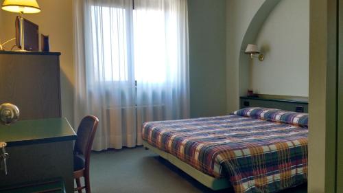 a bedroom with a bed and a window and a desk at Hotel La Goletta in Binasco