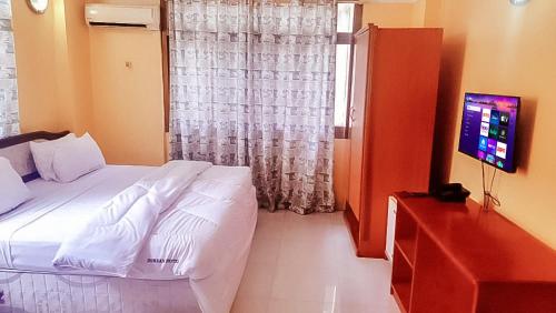 a bedroom with a bed with a television and a window at Durban Hotel in Dar es Salaam
