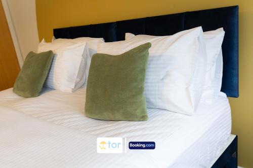 a bed with white sheets and green pillows at 2 Bedroom Apartment By The One Retreats Short Lets & Serviced Accommodation Horley Close To Gatwick Airport in Horley