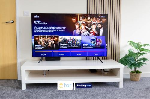 a tv sitting on top of a white tv stand at 2 Bedroom Apartment By The One Retreats Short Lets & Serviced Accommodation Horley Close To Gatwick Airport in Horley