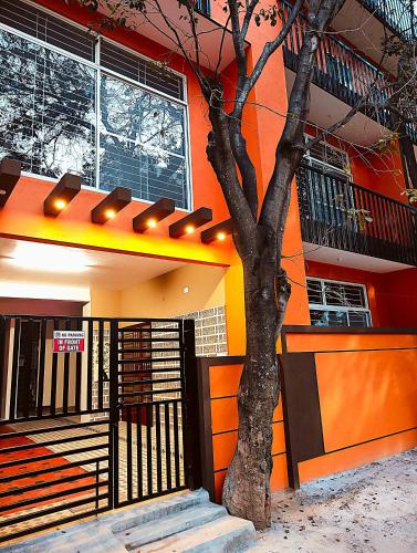an orange building with a tree in front of it at Samuels Comfort Homes in Bengaluru