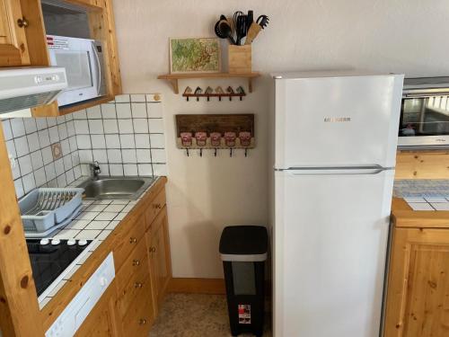 une cuisine avec un réfrigérateur blanc et un évier dans l'établissement Appartement 2 étoiles en pied de pistes et au centre ville 4 personnes, à Pralognan-la-Vanoise