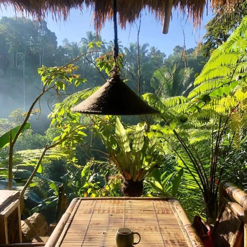 a table in a room with a view of a forest at Satu Lingkung in Tetebatu