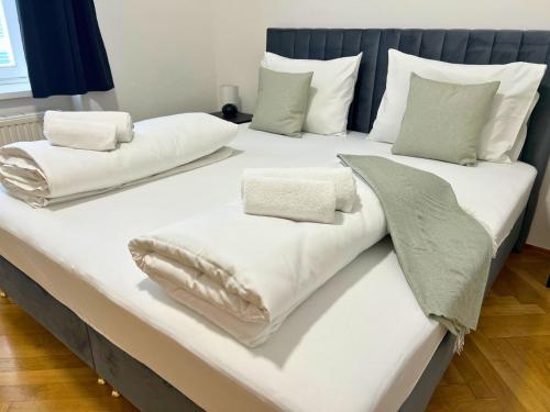 a large bed with white blankets and pillows on it at Leoben City Apartments - Premium Apartments 24 7 in Leoben