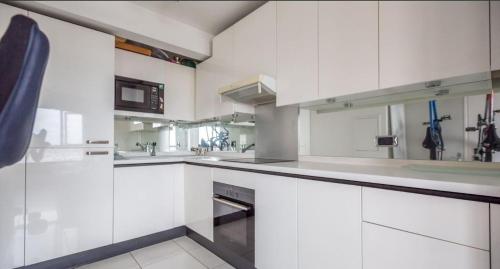 une cuisine blanche avec des armoires et des appareils blancs dans l'établissement Paris en hauteur, à Paris