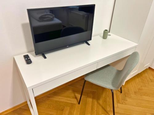 a tv sitting on a white desk with a chair at Leoben City Apartments - Premium Apartments 24 7 in Leoben