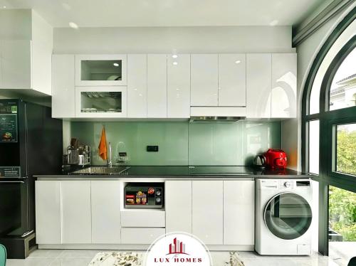 a kitchen with white cabinets and a washing machine at The LuxHomes Apartment ᵀᴹ I HOT Độc Đáo Nhất Vinhomes Marina in Hai Phong