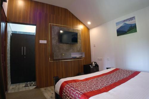 a bedroom with a bed and a flat screen tv at Mystery Maze Resort and Spa in Wayanad